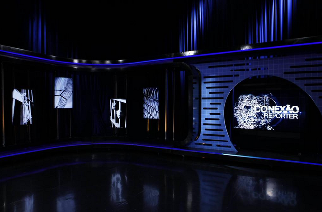 Cenário segue a ideia de um estúdio mais "sombrio", estilo dos jornalísticos das emissoras estadunidenses, como o "Dateline", da NBC